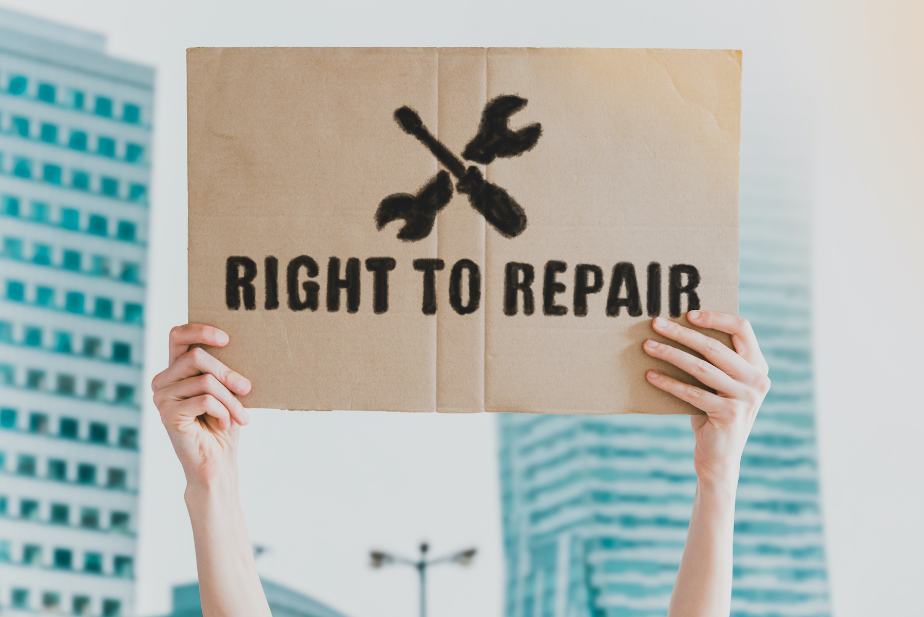 Person holding up a sign that says "Right to Repair."